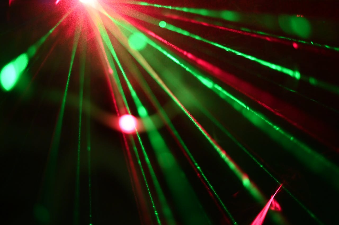 about-us Dynamic display of red and green laser lights creating vivid rays across a dark background.