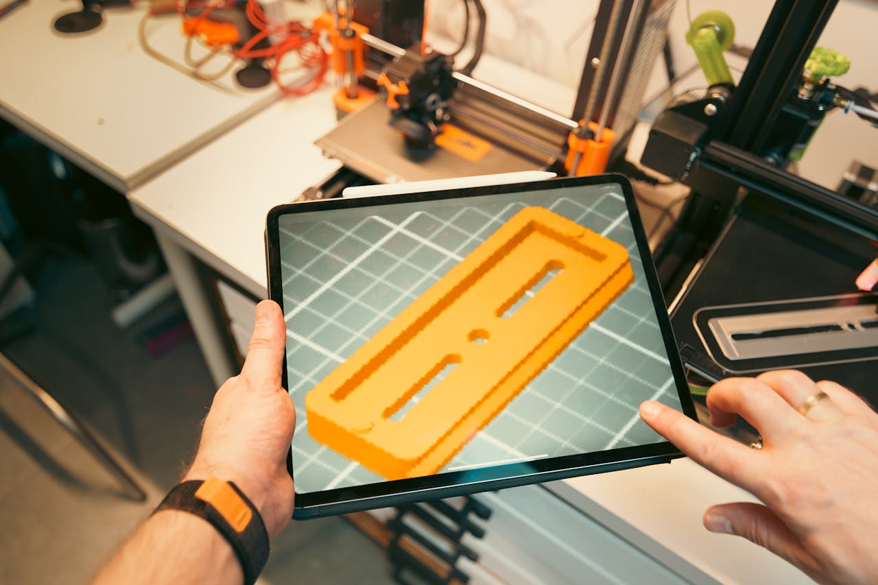 our-story A person uses a tablet to view a 3D model prototype in a workshop equipped with 3D printers.